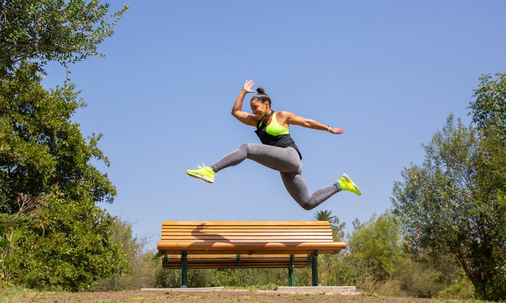 Woman Sprinting Over Park Bench