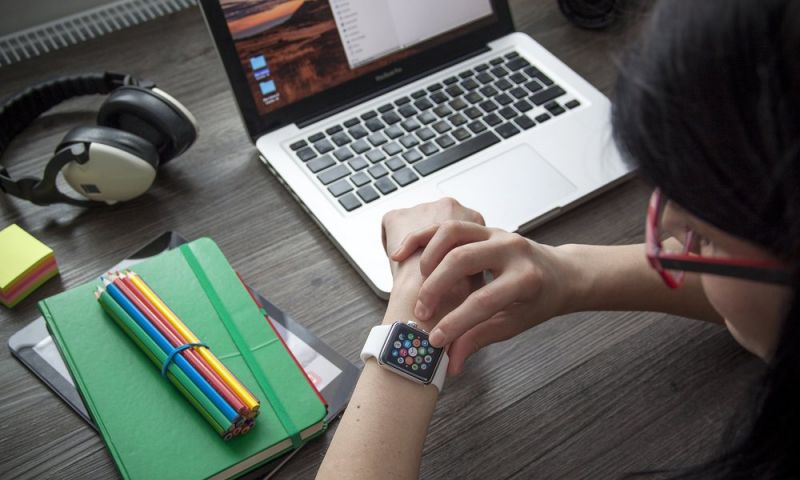 Woman Using Apple Watch At Desk With Macbook