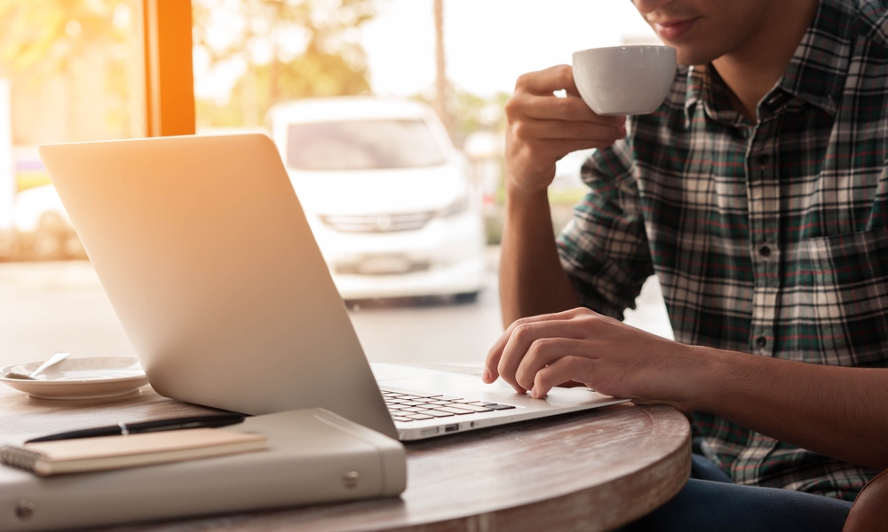 Man Drinking Coffee on MacBook In Coffee Shop