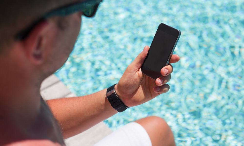 Man Using Smartphone by a Pool