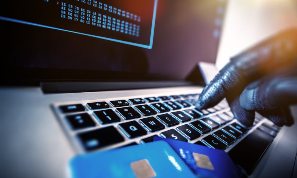 hacker gloved fingers on keyboard credit cards
