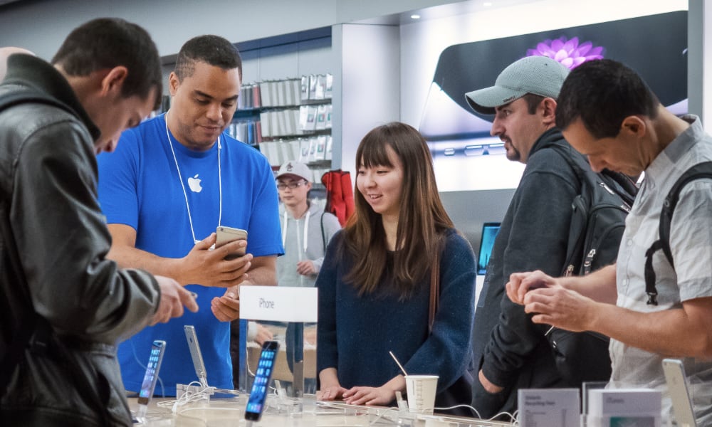 Apple Store customers around iPhone table