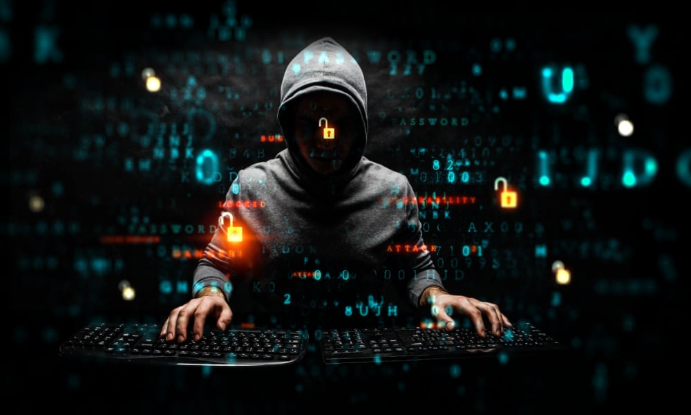 mysterious hacker in hoodie cybersurfing on two keyboards