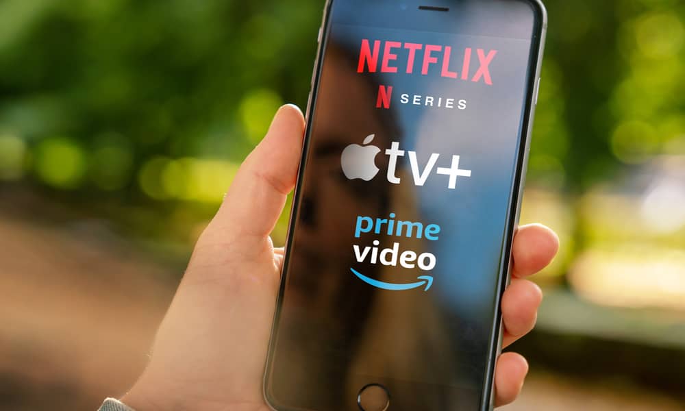 person holding phone showing Netflix Apple TV plus and Amazon Prime video logos
